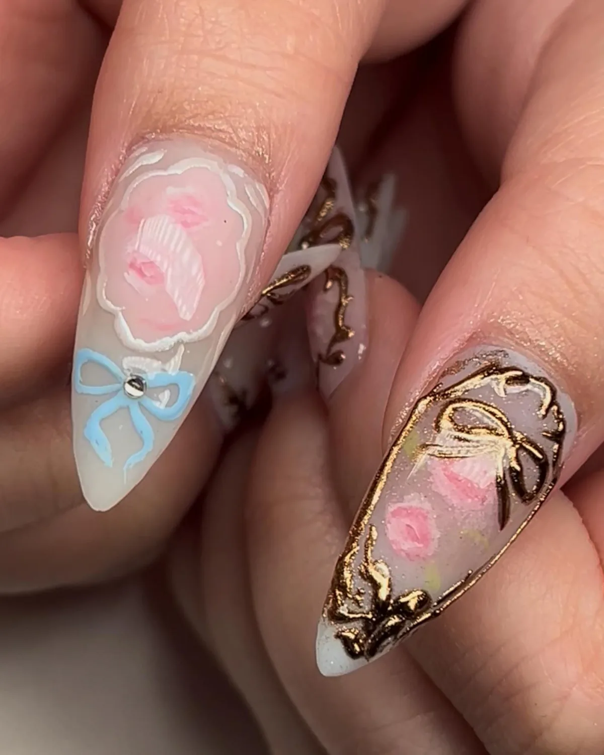 Fairy princess nails: a pink rose and blue bow painted on long almond nails with gold chrome