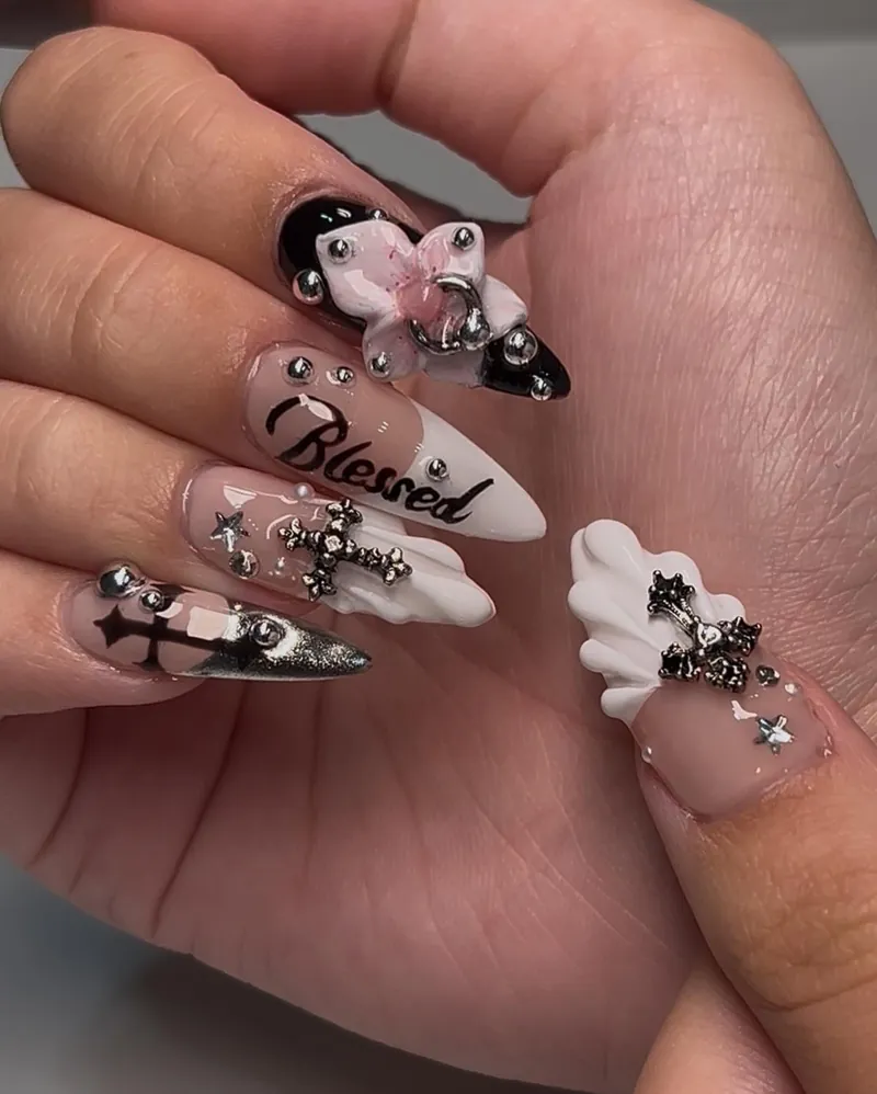 Long almond nails with black and silver chrome crosses, a 3D bow and 'Blessed' lettering